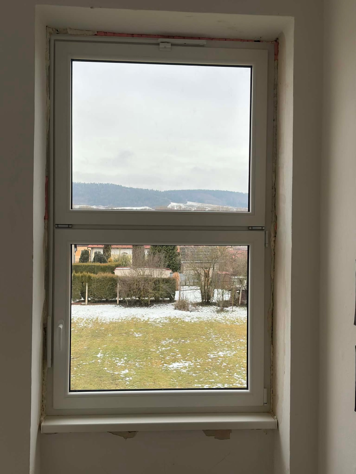 Vysoké biele okno s pohľadom na zasneženú krajinu
